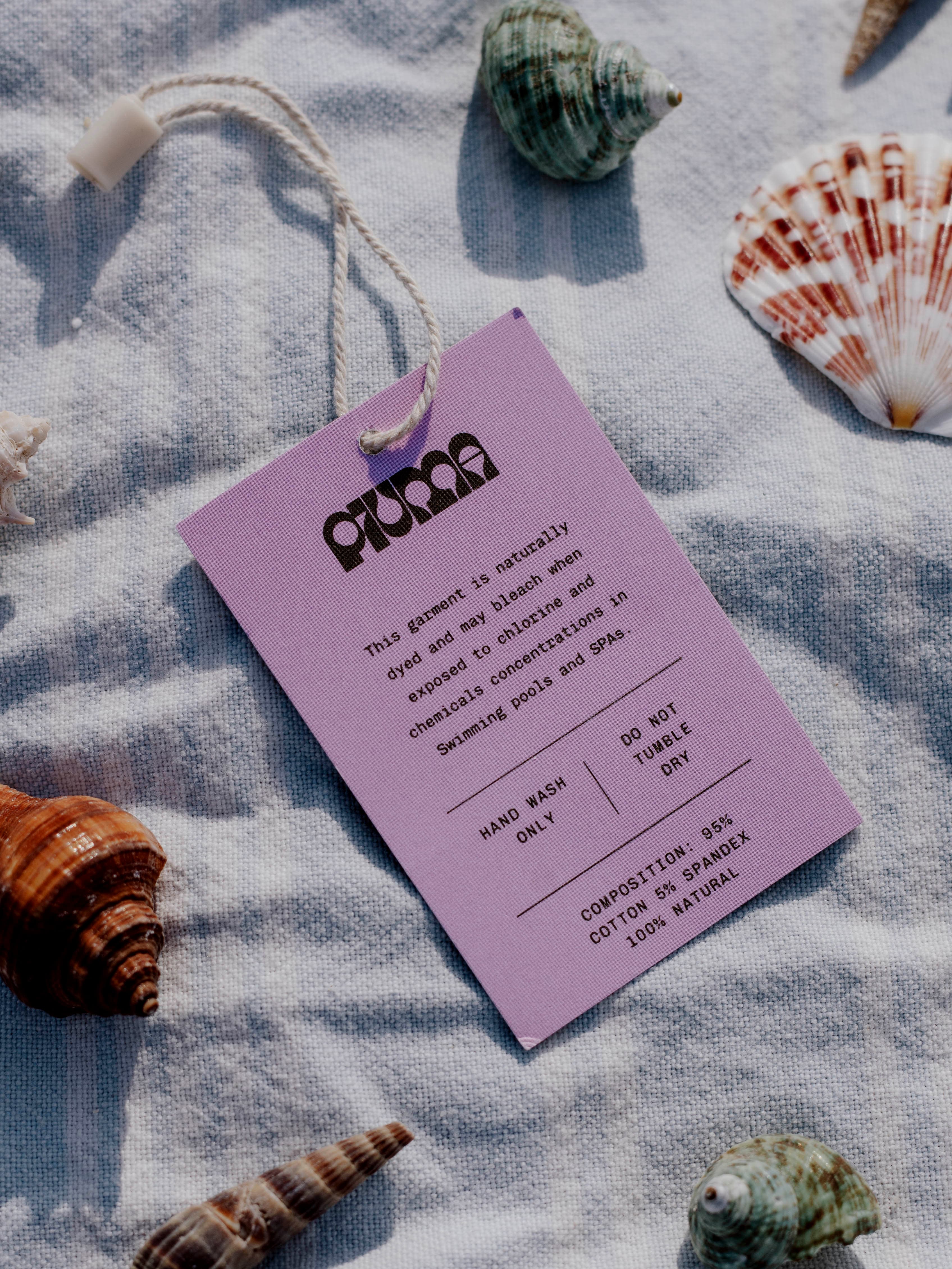 Piuma printed card styled with a towel, shells, and beach objects